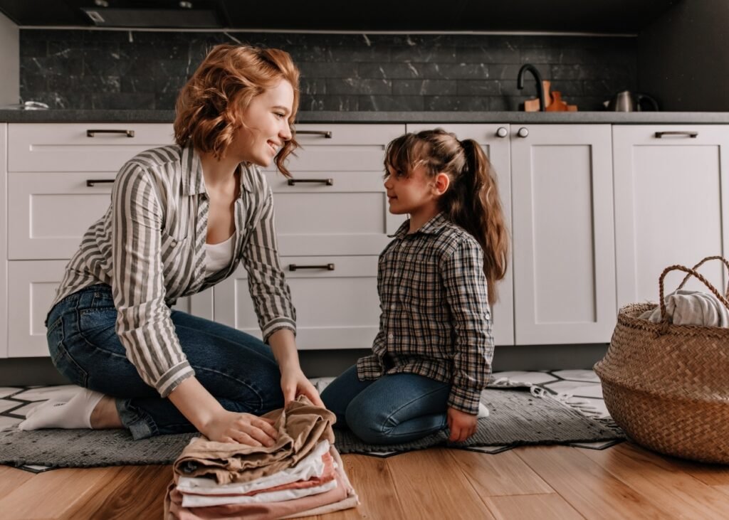 Édesanya és lánya ruhát hajtogatnak a konyhában.