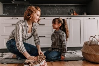 Édesanya és lánya ruhát hajtogatnak a konyhában.